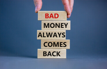Business concept growth success process. Wood blocks on grey background, copy space. Businessman hand. Words 'bad money always comes back'. Conceptual image of motivation.