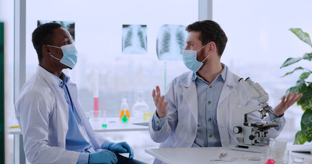 Multi-race couplke of scientists conducting research in medical laboratory. two biologists...