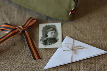 composition for the victory day from a soldier's cap with a Soviet retro star, a retro photo and a St. George ribbon on a linen background