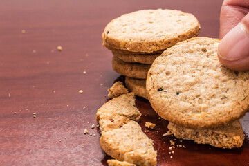 Holding a wholemeal biscuit on wooden table with copy space.