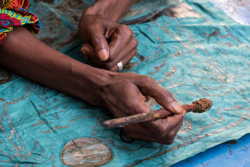 Manos de mujer decorando tela en un pueblo de Gambia