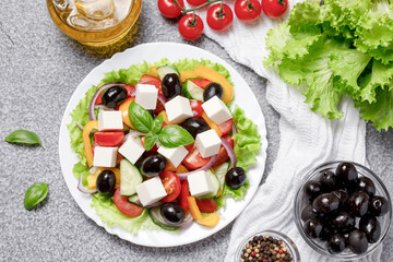 Greek salad with cheese and fresh vegetables on grey concrete background. Flat lay, top view. Healthy food concept. Flat lay, top view