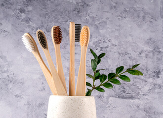 bamboo toothbrushes in a glass on a gray background