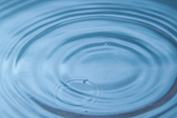 Circles on the blue water from falling raindrops. Close-up