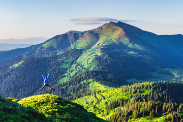 A tourist on the edge of a mountain covered with a lush grass