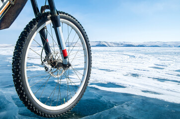 Bicycle on ice. Close-up of a studded bicycle tire on the background of an icy surface. Winter sport concept.