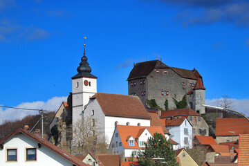 Obraz premium church close to a medieval castle in a village against blue sky