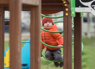 Obraz premium the child plays on the playground on the street, climbs the pipe on the slide, then to roll down from it. He's interested