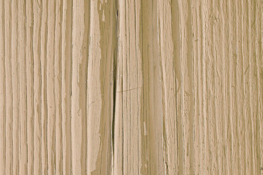 Light brown painted wooden surface. Dry old wood, cracked with age. Pale faded paint. Natural background, wallpaper or backdrop. Daytime sunlight with hard shadows. Close-up