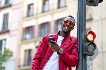 African man with mobile phone and sunglasses smiling