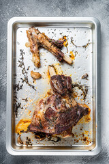 Roasted lamb mutton whole leg in a baking dish. White background. Top view