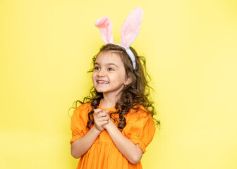 Obraz na płótnie Canvas funny happy girl with easter bunny ears on yellow background