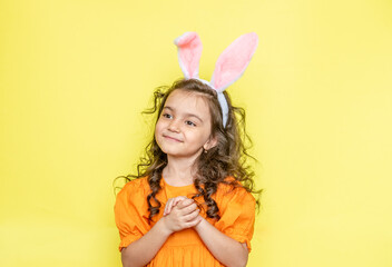 Obraz na płótnie Canvas funny happy girl with easter bunny ears on yellow background