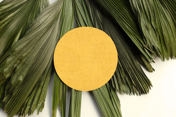 Blank brown round  paper on tropical palm dry leaves.