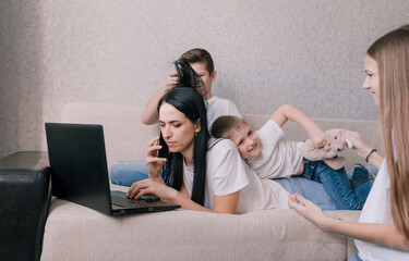 active children indulge, interfere and distract their mother while working at home on a laptop. working during a pandemic. freelancer remote work