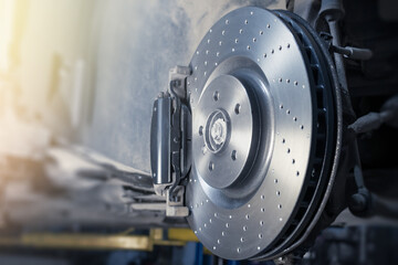 Installation of new perforated brake discs and pads on a modern auto in a car workshop. Blur effect. - obrazy, fototapety, plakaty