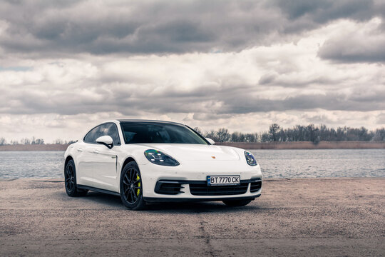 Kherson, Ukraine - March 2021. Hybrid Porsche Panamera 4 in a white color on the background of the river.