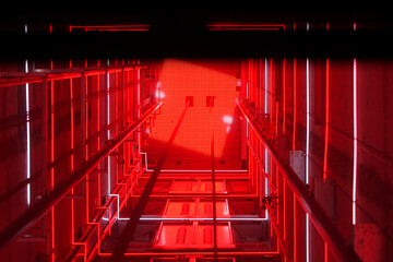 Lift shaft in a residential building. Elevator corridor in the building lit by red elumination....