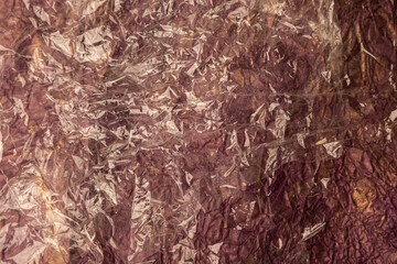 background from brown plastic film on colored paper concept of global pollution, waste, planet.