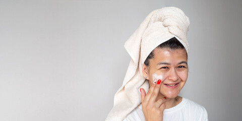 Young woman applying face cream on her face. Spa and wellness at home. Skin Care facial Concept. Banner with copy space