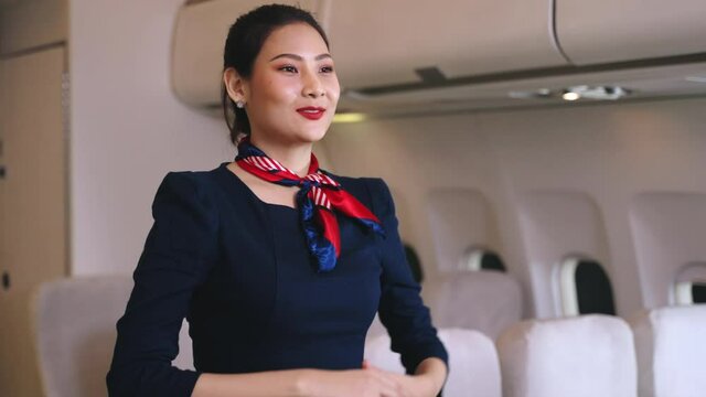 Flight attendants on demonstration aircraft in emergencies, Female flight attendant points out emergency exits during safety briefing in commercial airline main cabin.