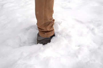 Man legs standing in fresh snow. Footprints of shoes in the snow. Snowdrifts in the winter