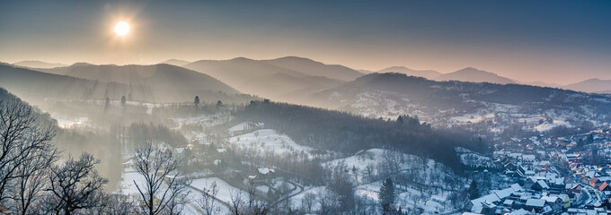 Sunrise over the mountains and village in winter panoramic shot