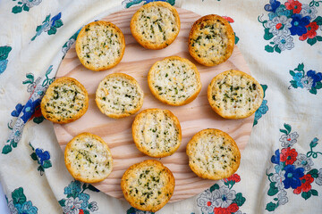 Toma en primer plano de un plato de madera repleto de pan tostado con aceite, ajo y perejil.
