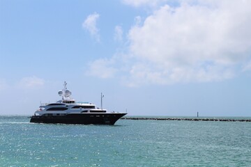 Obraz premium Gigantic big and luxurious yacht sailing through Miami Beach, Florida near South Pointe Pier, nearing the port. Copyspace Advertising. Investment for millionaires. Faces blurred out