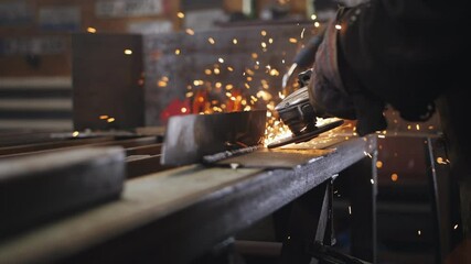 Sparks fly away from the grinder in the hands of a mechanic grinding a metal part in an auto repair shop - Powered by Adobe