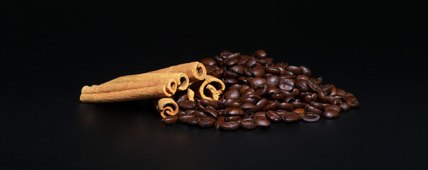 Roasted coffee beans and cinnamon on a black background.