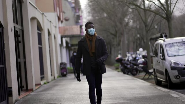 Elegant African man walking in slow-motion wearing face mask prevention against pandemic