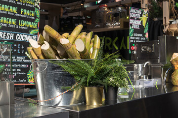 Sugarcane in a bowl, coconuts on the counter at Spitalfields food hall at the flea market.