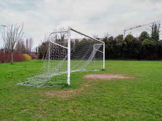 Fototapeta premium Football goal post on a training ground. Worn out grass on a keeper spot. Soccer theme background