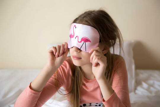 Beautiful young brunette takes off a sleeping mask, with eyes set aside, girl woke up in the morning, the concept of a happy start to the day