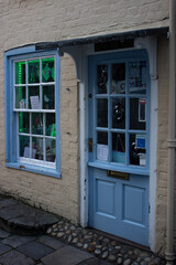 Fototapeta na wymiar Light blue door and window in a typical and ancient shop of a little street somewhere in England.