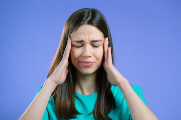 Obraz premium Portrait of woman having headache, violet studio portrait. Girl putting hands on head. Concept of migraine problems, medicine, illness