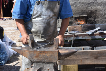 blacksmith forges iron  in open air workshop in old fashion, front of iron furnace