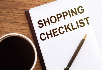 Shopping Checklist - text on notepad on wooden desk.