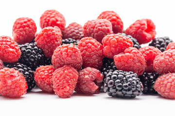 pile raspberries and blackberries on white background