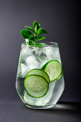 glass of water with cucumber and mint on a black background