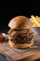 Freshly cooked organic marble beef burger, cheeseburger with fresh farm vegetables, onion, salad leaves, tomatoes, bbq sauce, french fries served as a main dish in a fancy restaurant during lunchtime