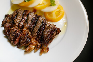 Organic, succulent, and freshly cooked rib-eye steak, new york steak,  butcher steak, served with fresh onion and yellow tomatoes