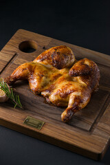 Freshly roasted organic chicken put on a wooden plate with grilled garlic and rosemary