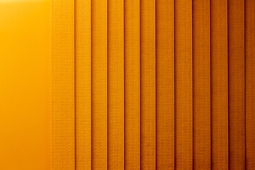 Full frame abstract art design background of vertical window blinds along a textured wall, in a...