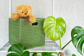 A toy bear peeks out of a large green storage box. Grid system for organizing storage in a modern home