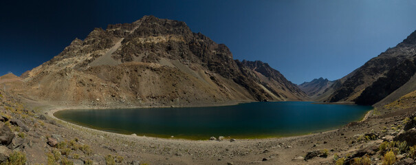 Panorama view of the popular Inca lagoon in the Andes mountains in Chile. The turquoise glacier water lake very high in the cordillera, surrounded by rocky mountains and the arid desert.