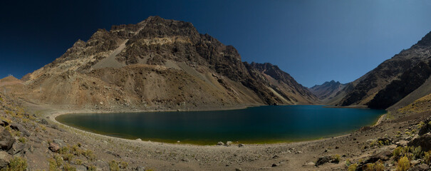 Panorama view of the popular Inca lagoon in the Andes mountains in Chile. The turquoise glacier water lake very high in the cordillera, surrounded by rocky mountains and the arid desert. 
