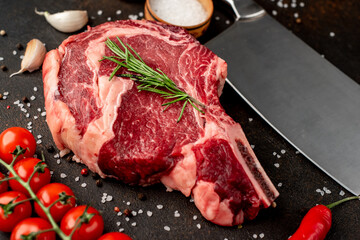 raw  ribeye steak with spices on a stone background
