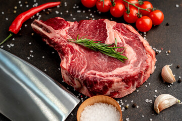 raw  ribeye steak with spices on a stone background